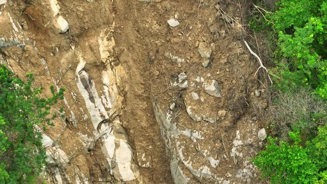 Aerial shot capturing the aftermath of an extreme weather event, with mudslide and uprooted trees disrupting a lush forest, illustrating nature&rsquo;s vulnerability to harsh conditions. Thailand.
