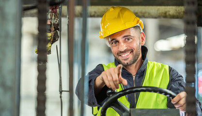 Portrait of forklift truck driver man smiling in old factory warehouse lifting pallet in storage...
