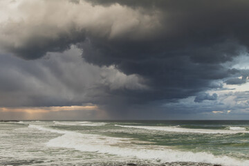 Dark storm clouds swirling over a rough but sunlit sea with the late afternoon sun breaking through...