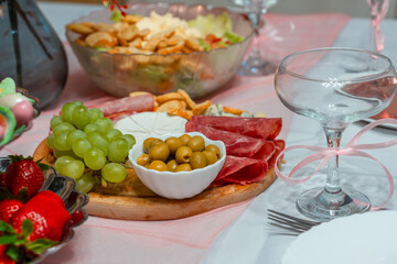 Festive table with a plate of cheese, grape appetizers, salad