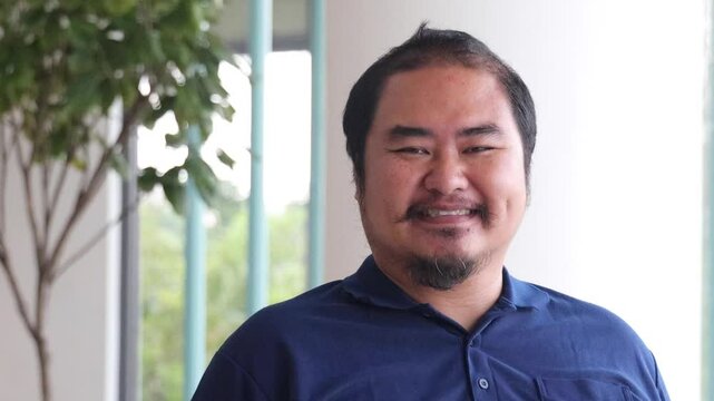 Happy smiling friendly middle aged Asian man, aged man with overweight and hair loss as signs of aging