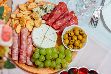 Festive table with a plate of cheese, grape appetizers, salad
