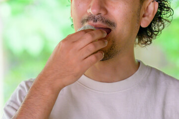 和菓子をつまんだ男性がゆったりとした表情で口元に運ぶ夏の一瞬を切り取ったライフスタイル