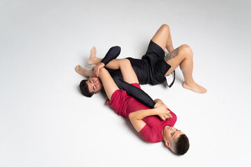 Two young men performing a leg lock in mma sparring on white background