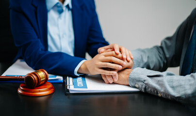 Lawyer offering emotional support to client with hand on hand above legal contract. Justice,...