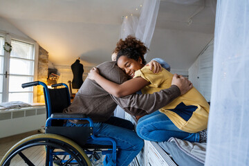 Multiethnic, diverse daughters and single father in a wheelchair sharing a warm moment at home