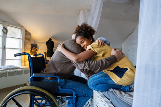 Fototapeta Multiethnic, diverse daughters and single father in a wheelchair sharing a warm moment at home