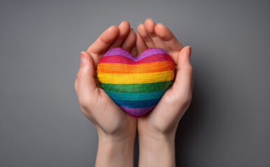 Beautiful hands holding colorful rainbow heart symbolizing love and acceptance, conveying message of unity and pride