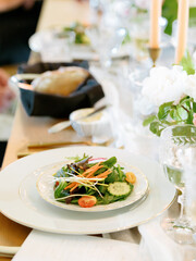 Elegant plated salad on a formal table setting with flowers