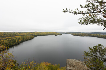 Overcast lake view from rocky cliff surrounded by autumn forest