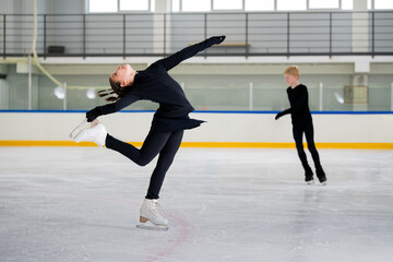 Young figure skaters practice their elements on  skating rink.