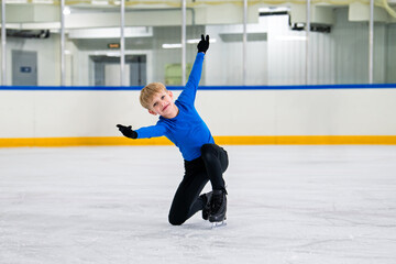 boy figure skater skates on an indoor rink, demonstrating balance .