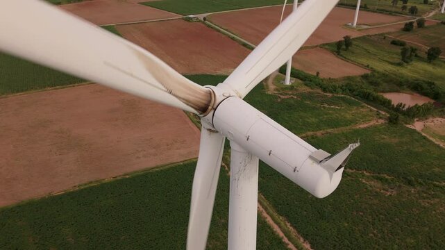 Detailed drone view of a wind turbine with visible oil stains and wear marks on the hub and tower, highlighting the need for technical maintenance and inspection.