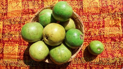 Top view of Fresh ripe guavas stacked in wicker basket with designer pattern background. These jaam phal guava fruits are red inside
