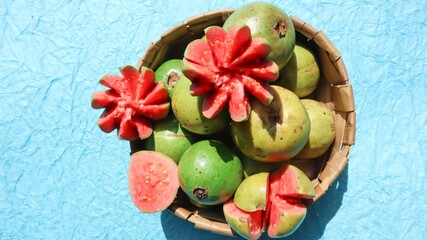Fresh Guava fruits carved in flower shape with red pulpy inside. Jaam phal amrood fruits in wicker basket