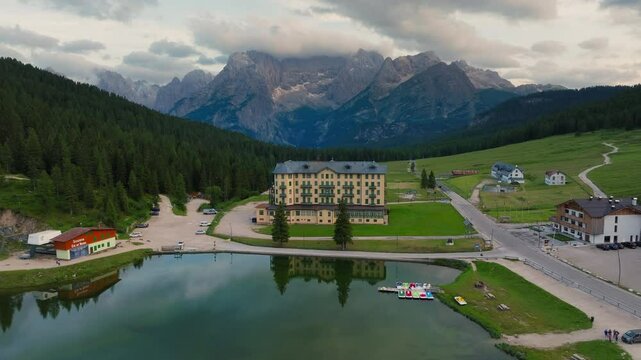 Lago di Misurina natural lake in Dolomites surrounded by alpine mountains and coniferous forests at sunset, Drone shot