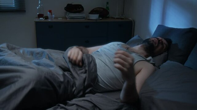 Middle aged man sleeping restlessly and suffering from night terrors waking up at night