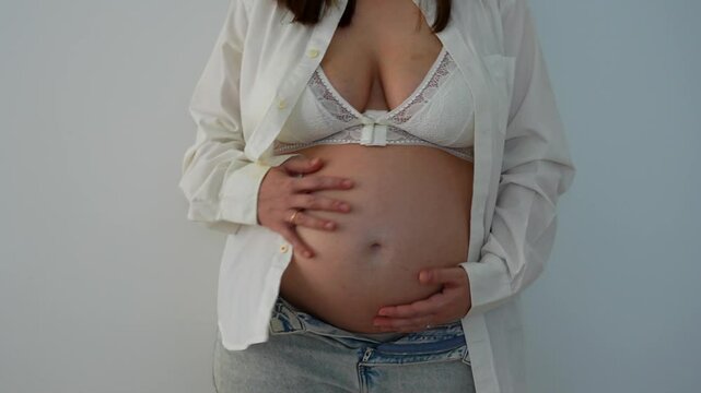 Young woman with 36 weeks pregnant belly, medium shot on a white background