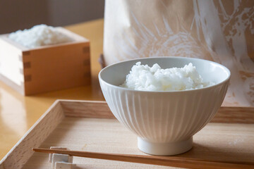 トレイの上の茶碗に盛ったご飯と箸、枡に入った白米と米袋