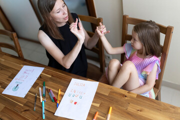 Teacher helping young girl with sign language at home