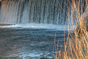 A dam with water cascading down like a waterfall. The powerful flow demonstrates controlled water...