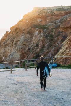 Surfer walking at sunset in sagres, algarve, portugal