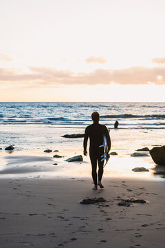 Surfer watching the waves at sunset on the beach in portugal