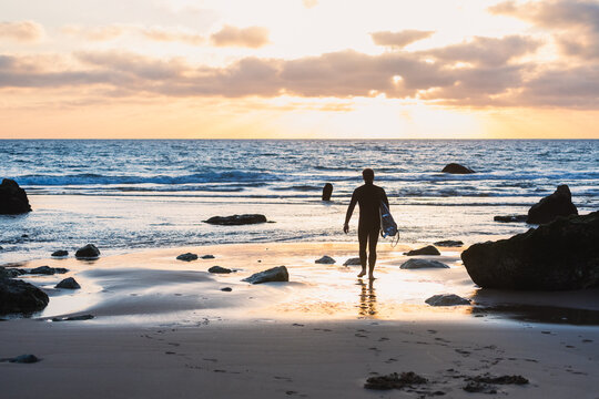 Surfer watching the waves at sunset on the beach in portugal