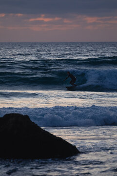 Surfer riding wave at sunset in algarve, portugal