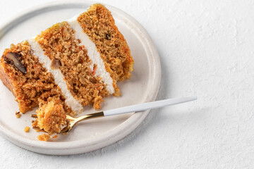Homemade layered carrot cake with cream cheese, walnuts and spices on a plate with dessert fork