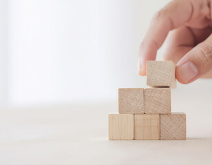 Close up hand and stack of wood block cube on the table.
