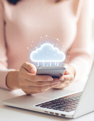 Photography of a person using the phone and labtop with cloud icon on the screen.