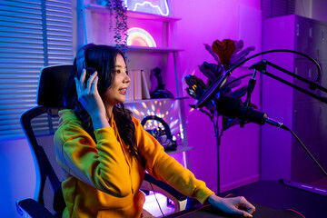 Asian audio DJ woman talking on microphone to broadcasting in neon room. 