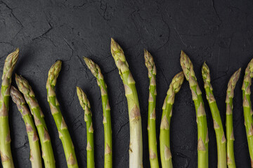 Fresh green asparagus spears on black textured background