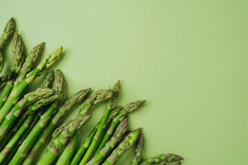 Green asparagus spears aligned on green background flat lay
