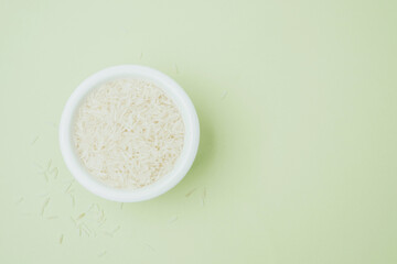 White rice in ceramic bowl on green pastel background