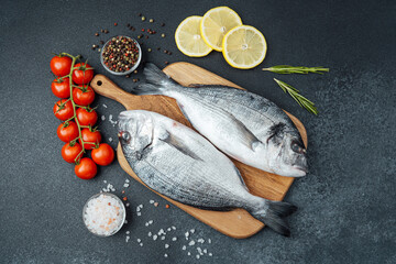 Raw dorado fish tomatoes lemon and spices on cutting board