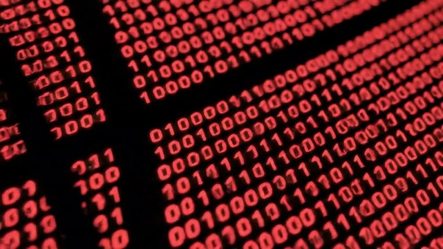 A close up shot of red binary code on a black screen displaying data and information flow pattern