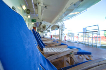 Outdoor promenade boat pool deck onboard modern luxury cruiseship cruise ship ocean liner with sun loungers and deck chairs for guests passengers with ocean views