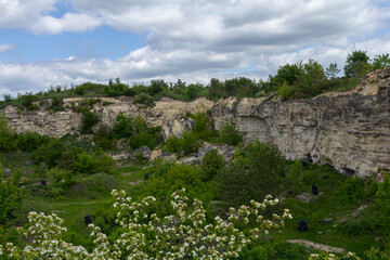 Vast green landscape of a former quarry showcasing steep cliffs and flourishing vegetation under a...