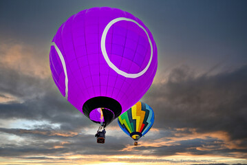 Colorful hot air balloon flying under orange sunset sky