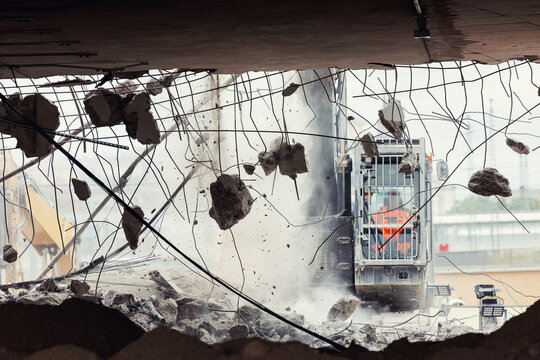 Close-up view of crumbling bridge structure demolition in Magdeburg Damaschkeplatz  exposed steel rebar falling concrete chunks. Rubble piles and demolition machinery emphasize destruction progress