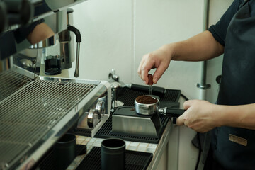 Closeup male barista preparing portafilter with coffee grounds at espresso machine inside cafe, demonstrating artisan precision, passion, and dedication of small family coffee business, small business