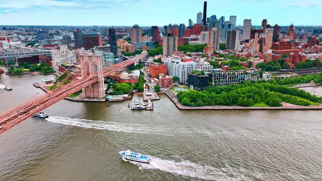 Beautiful park and green area at the waterfront of the East River and nearby the Brooklyn Bridge. Boats move by the river. Aerial perspective on New York, USA.