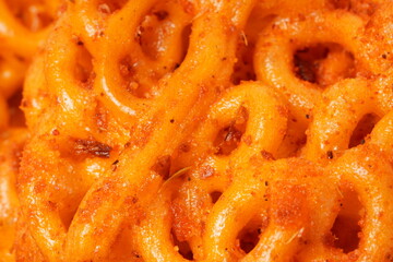 A pile of spicy Indonesian crackers or Kerupuk with spiral twists, coated in red-orange chili powder and rich spices. Bold, flavorful, and appetite-boosting. Photographed against a white background.