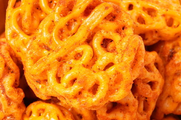 A pile of spicy Indonesian crackers or Kerupuk with spiral twists, coated in red-orange chili powder and rich spices. Bold, flavorful, and appetite-boosting. Photographed against a white background.