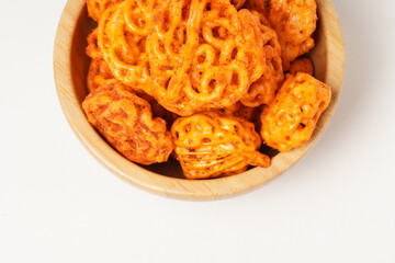 A pile of spicy Indonesian crackers or Kerupuk with spiral twists, coated in red-orange chili powder and rich spices. Bold, flavorful, and appetite-boosting. Photographed against a white background.