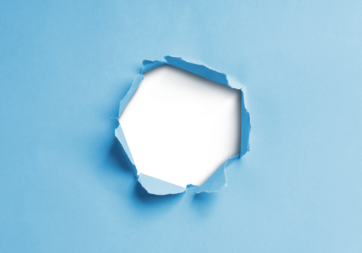 Close-up image of a blue paper sheet with a jagged hole torn through the center, revealing a transparent background.
