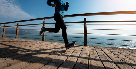 Sporty female jogger morning exercise on seaside boardwalk during sunrise