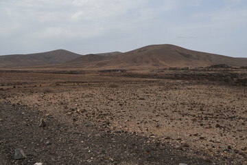 volcanic arid landscapes with trils, cliffs, and scattedred vegetation.